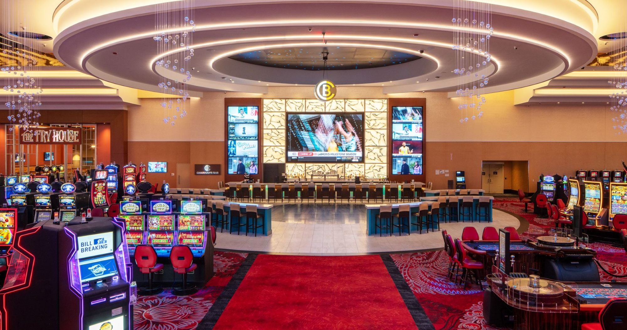A casino floor filled with lots of slot machines and large screen televisions.