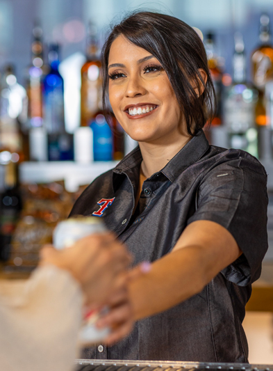 A smiling employee handing a guest a beverage.