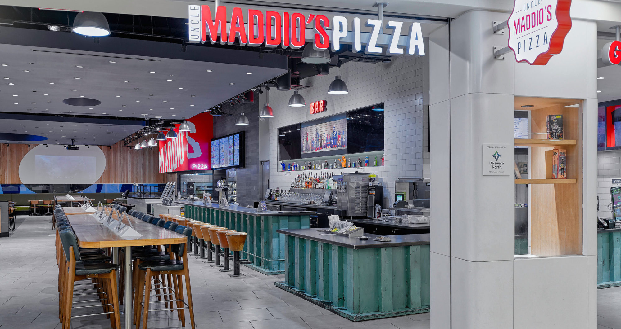 The interior of Uncle Maddio's Restaurant with a bar, tables, and stools.